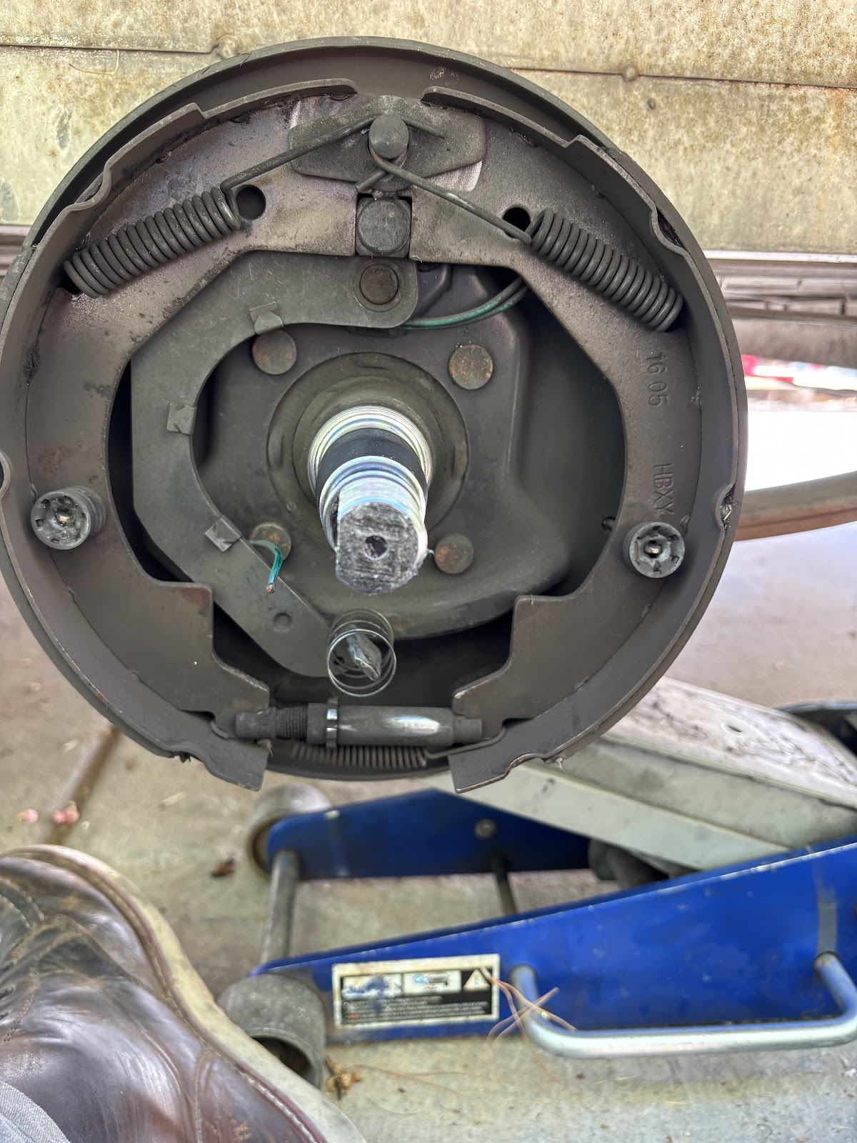 Drum brake assembly opened up for service over a blue floor jack