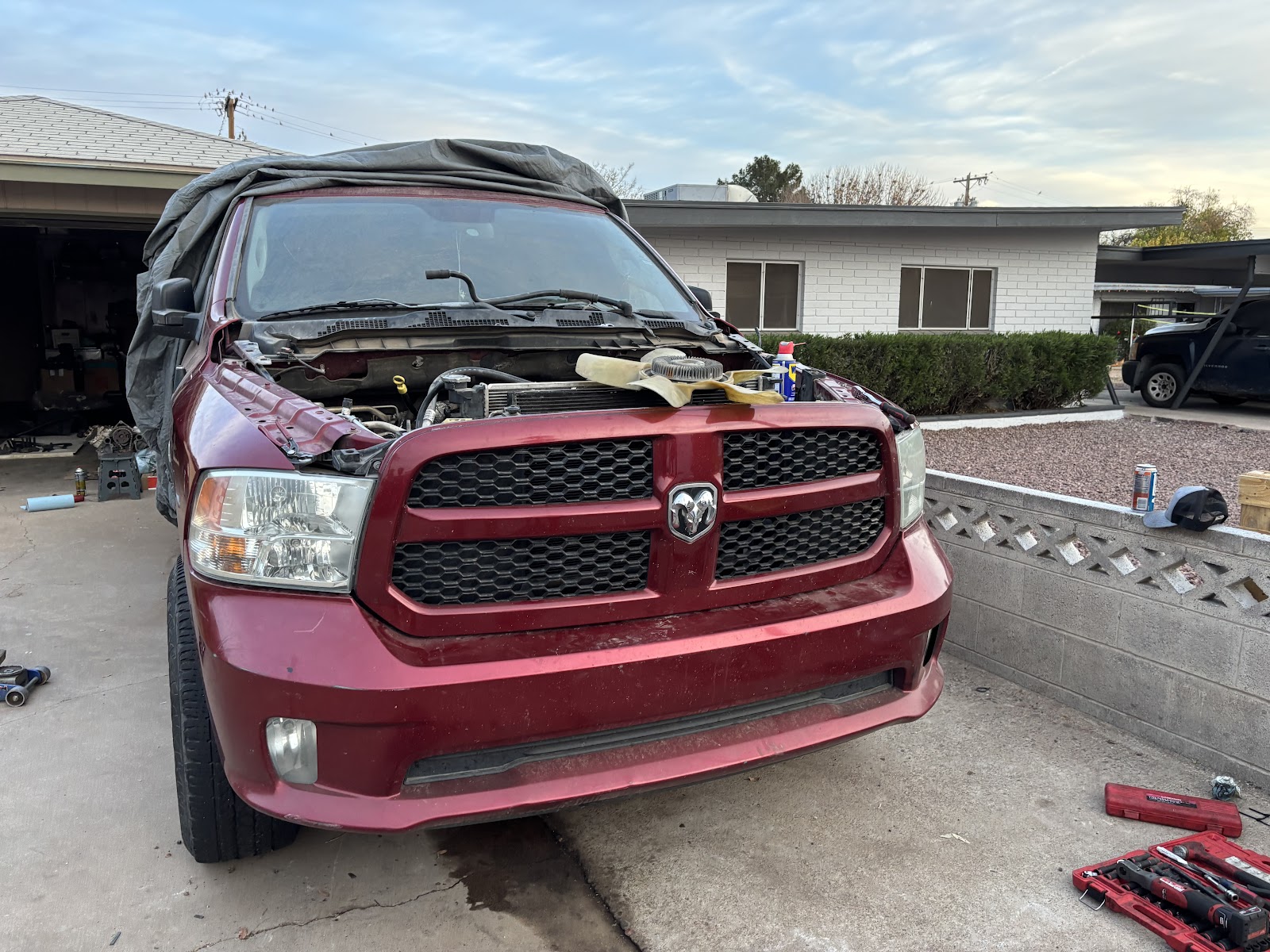 Dark red Ram truck in a driveway with its cooling fan removed and resting on the grille