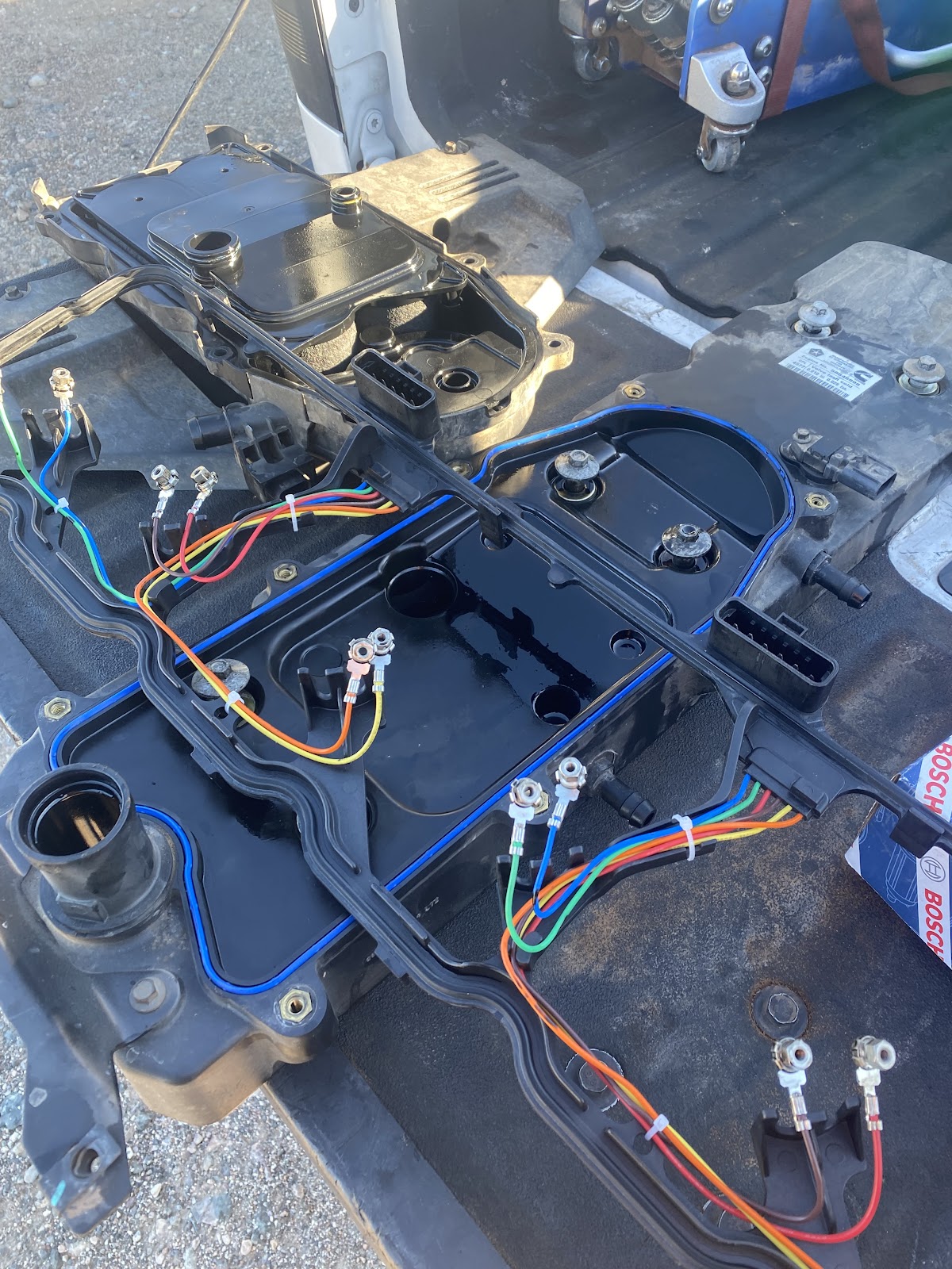 Transmission parts and new solenoid wiring laid out on a tailgate with a new Bosch part box